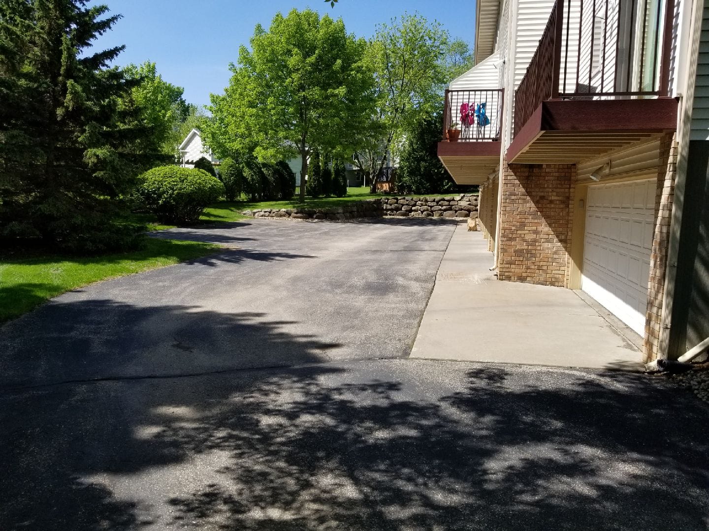 Residential driveway sealcoating showing fresh coat under shade trees