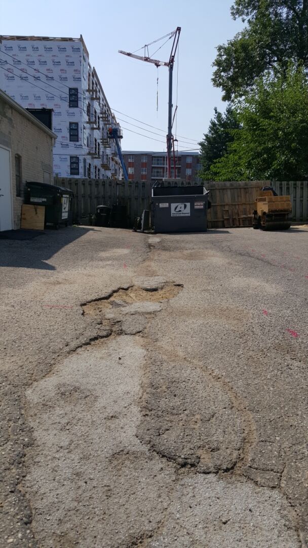 Damaged asphalt with potholes before infrared patching repair in Madison, WI