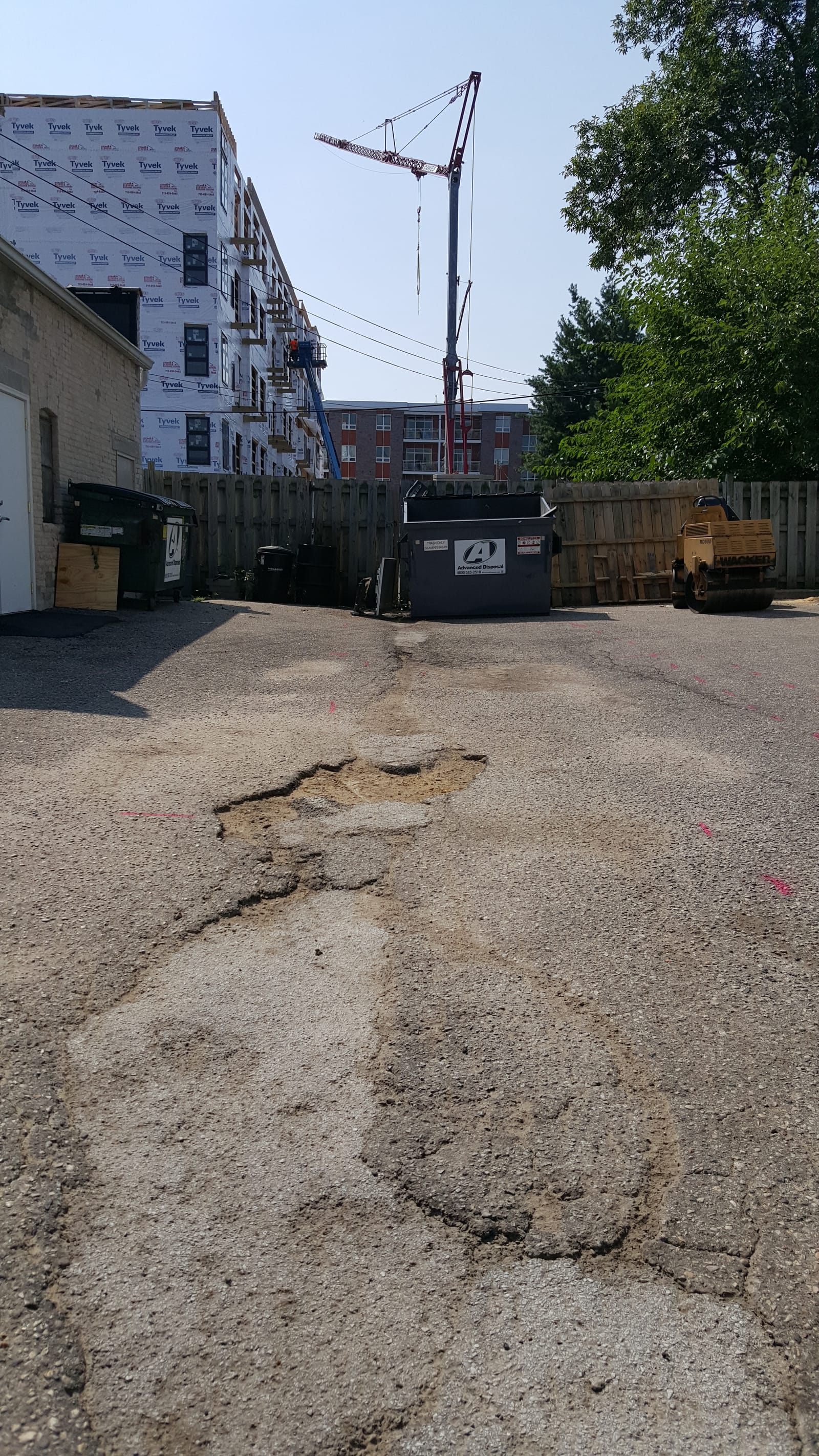 Broken, cracked asphalt with deep pothole damage before infrared patching repair in Madison, WI