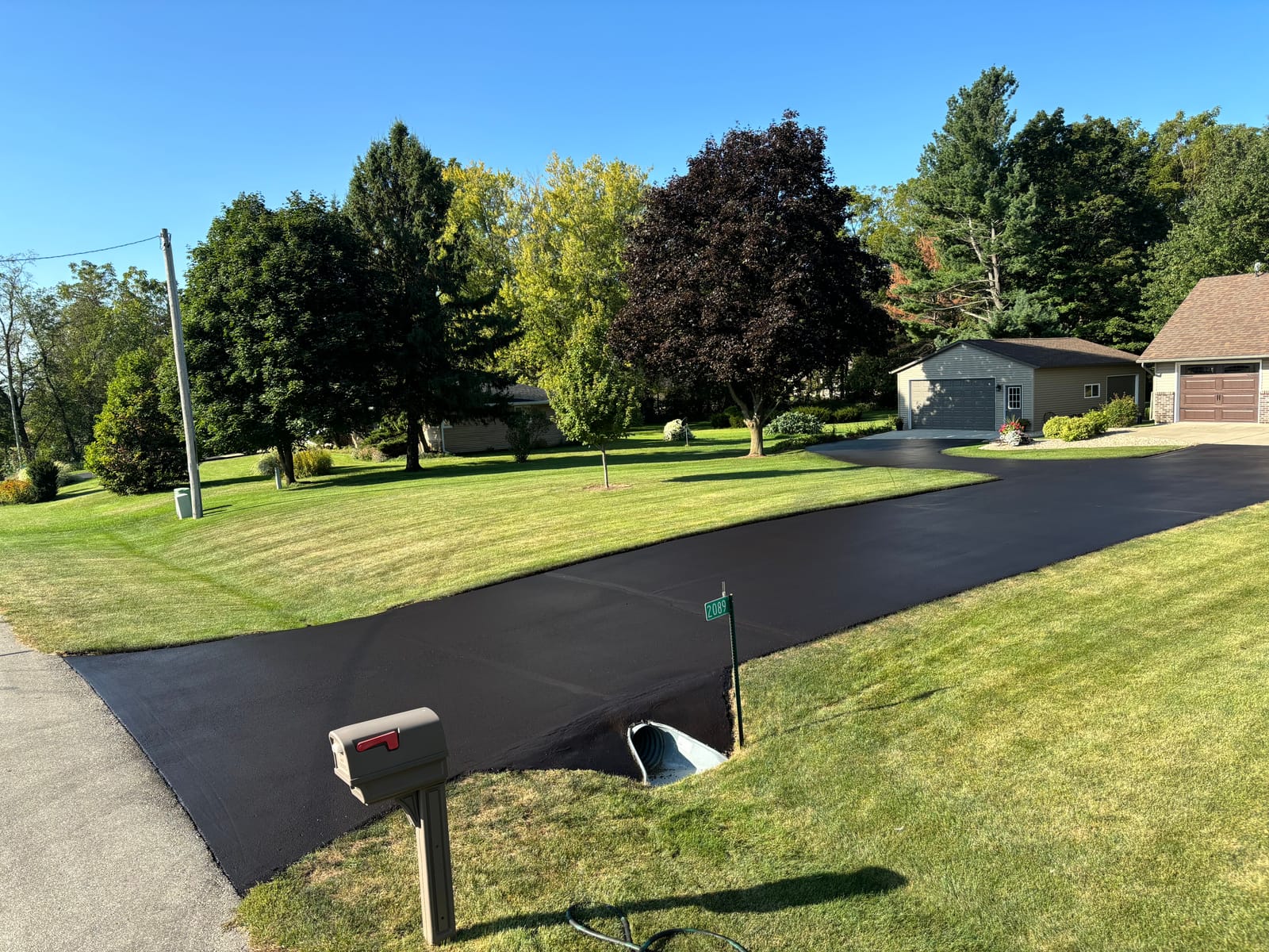 Freshly sealcoated residential driveway with mailbox in Madison, WI