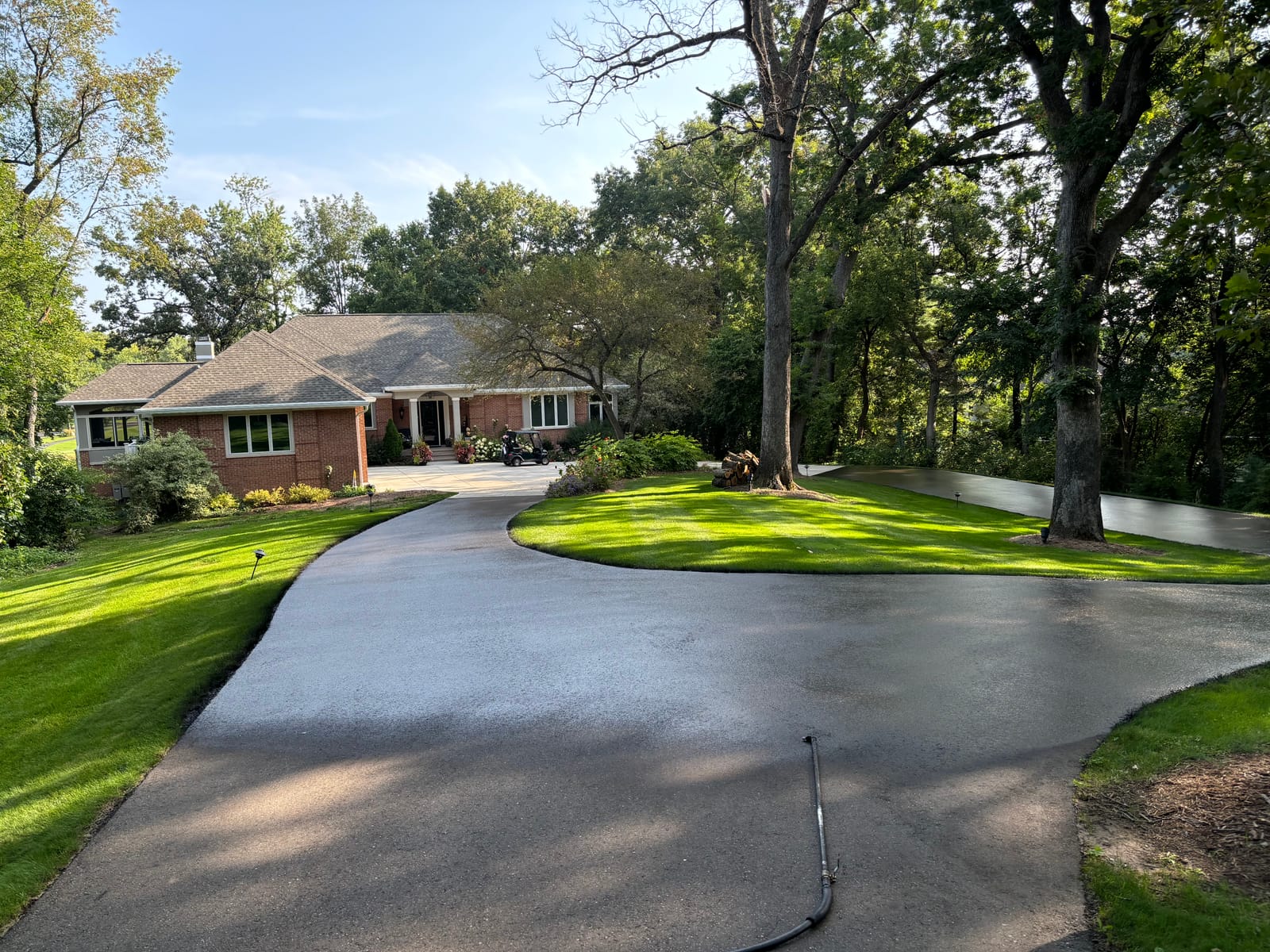 Curved residential driveway sealcoating in front of brick home in Wisconsin