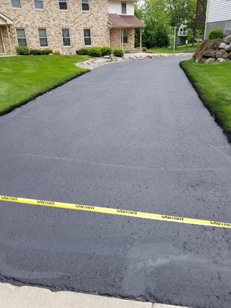 Freshly sealcoated residential driveway with caution tape in Madison, WI