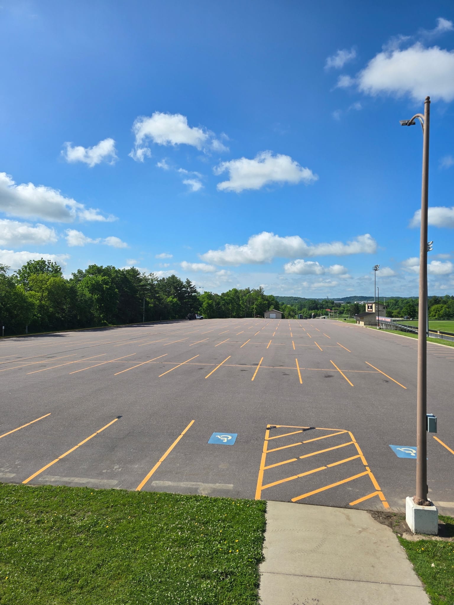 Faded asphalt parking lot with worn striping before sealcoating in southern Wisconsin